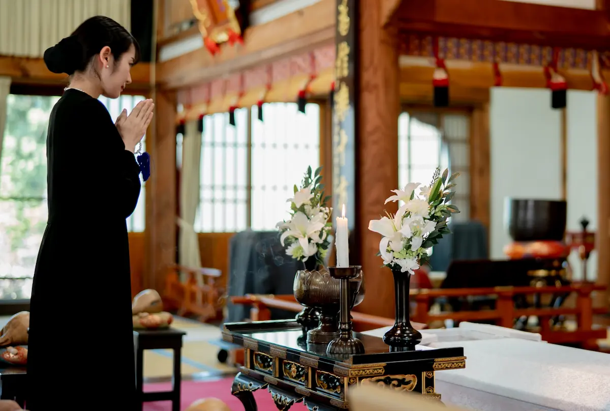 寺院の祭壇に向かって焼香する女性