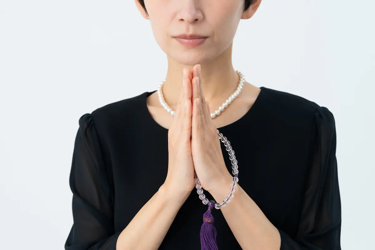 家族葬の通夜で合掌する女性の画像