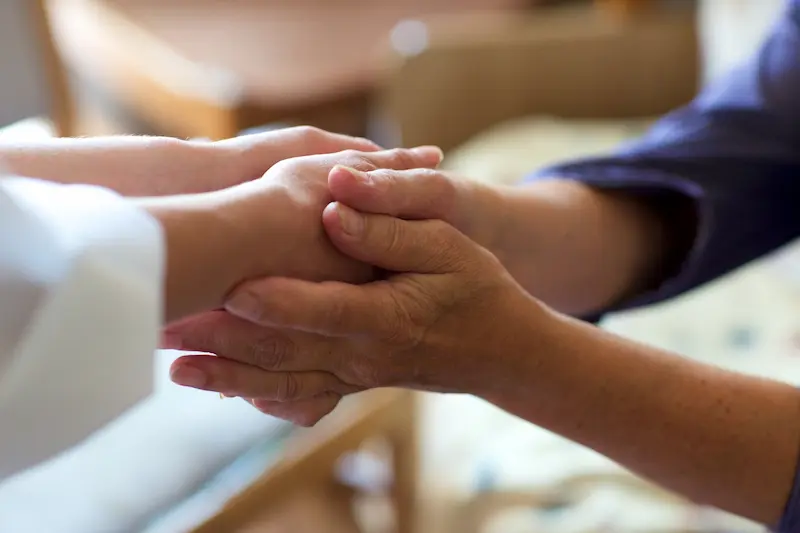 病室で故人と家族が手を取り合っている画像