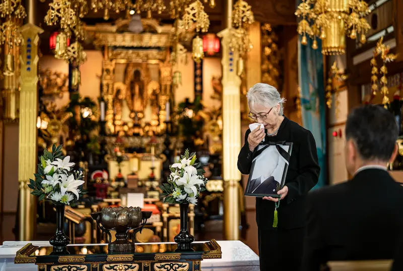 喪主が遺影を手にして涙する様子