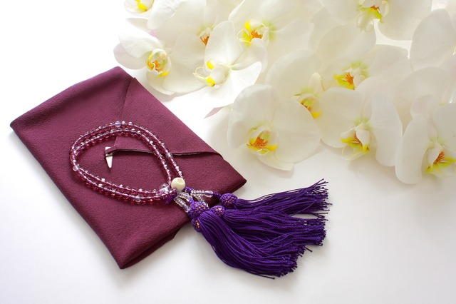 紫色の袱紗と数珠と胡蝶蘭の画像
